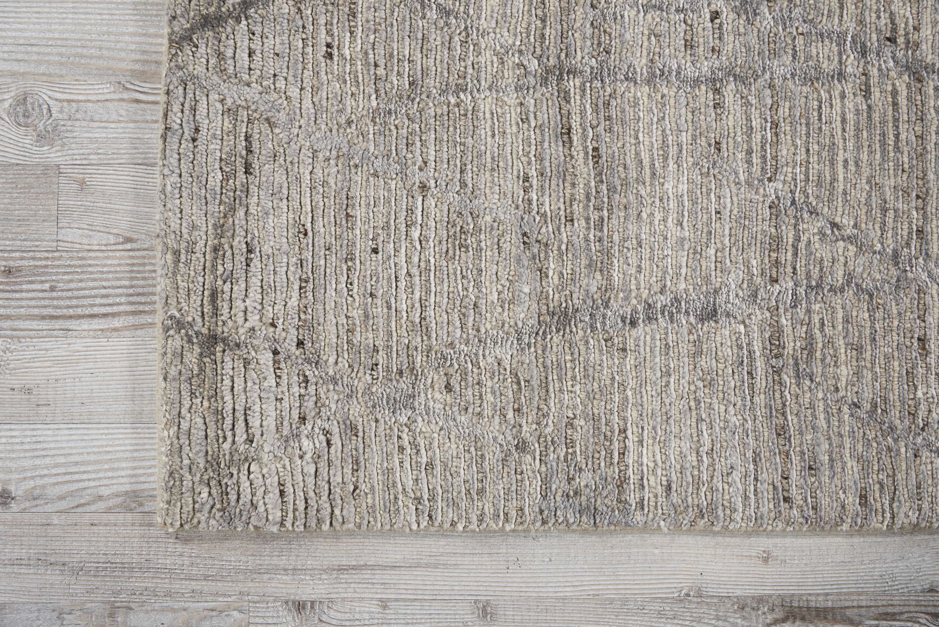 Close-up view of a textured rug meeting a wooden floor.