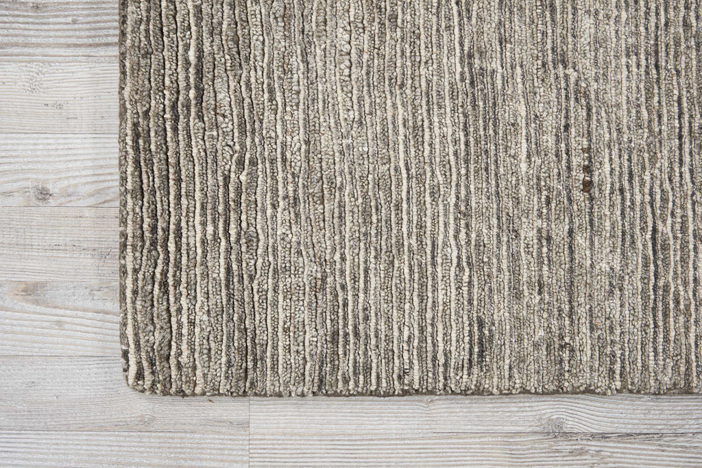 Textured rug with striped pattern on wooden floor, contrasting textures.