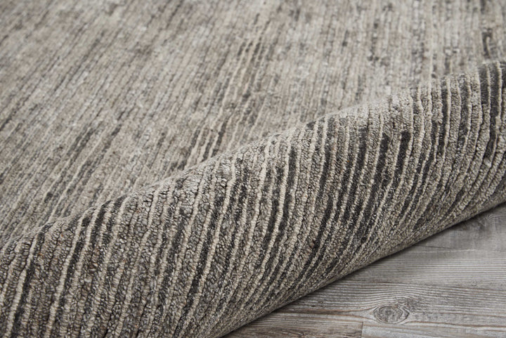 Textured rug with folded corner on weathered wooden floor.