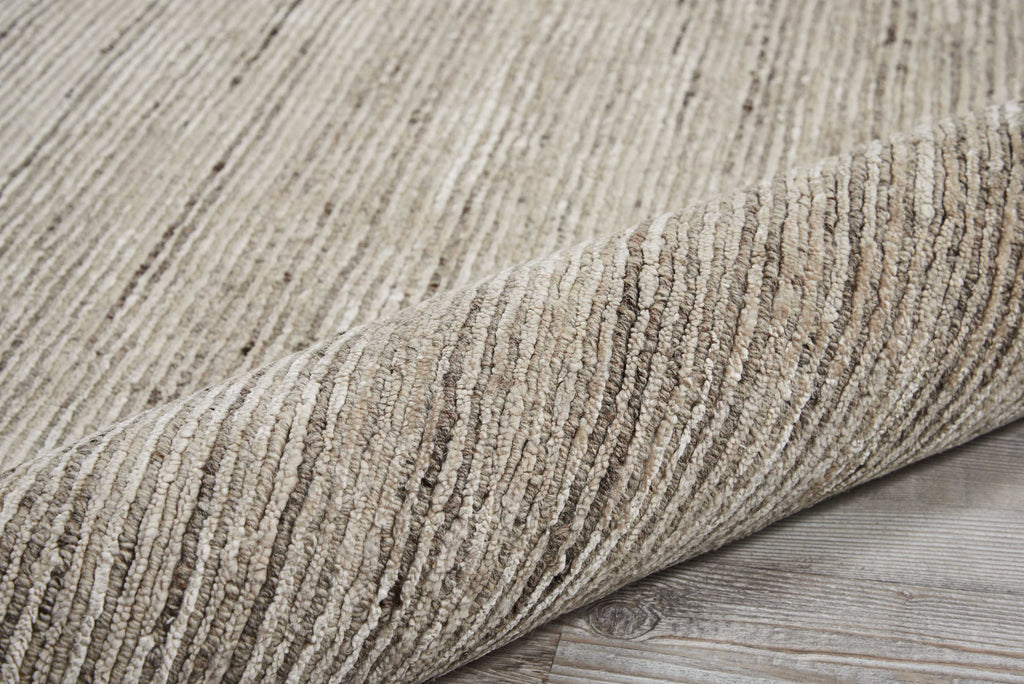 Close-up of a rolled-up, striped rug on a wooden floor.