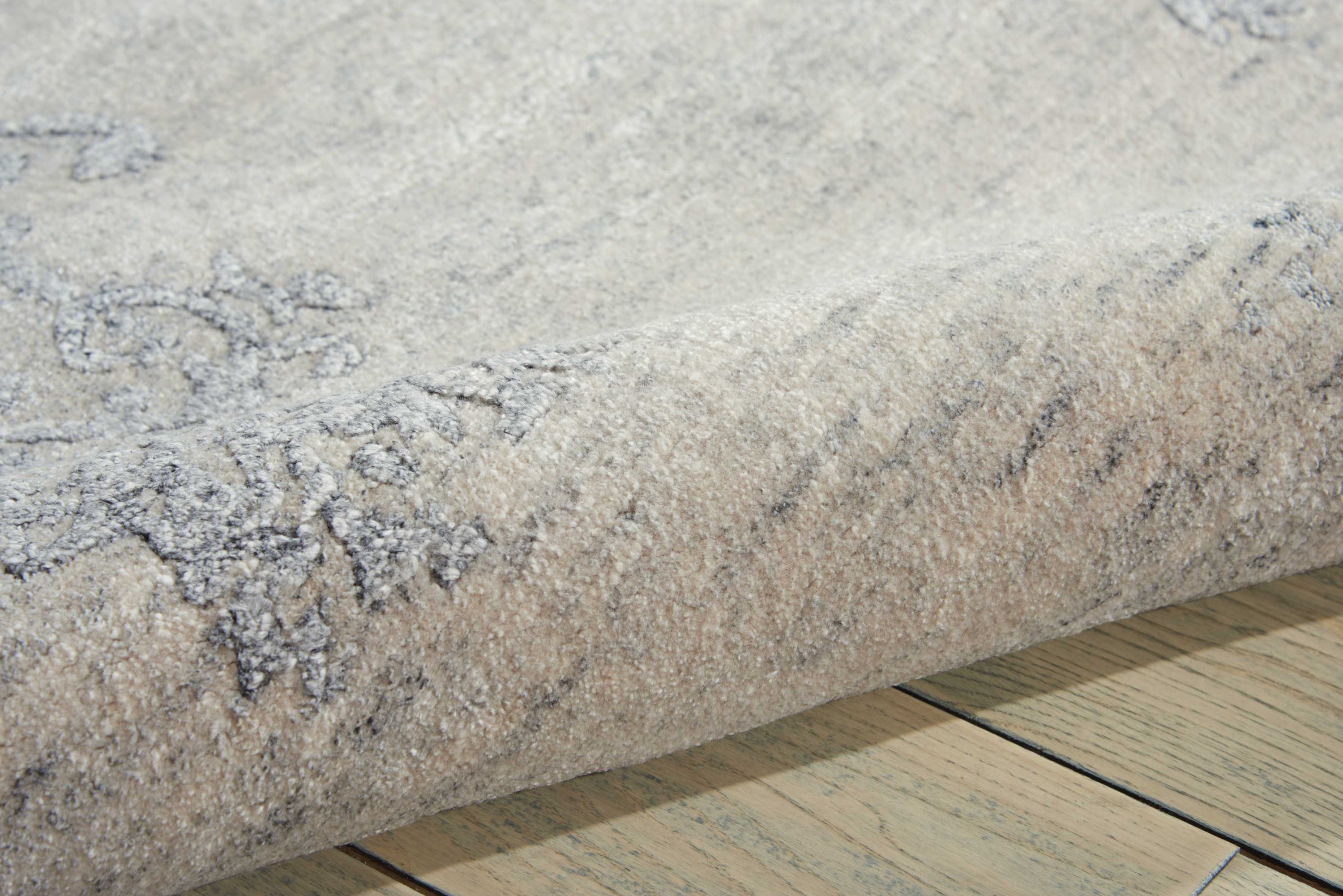 Close-up view of plush, textured carpet with wooden floor.