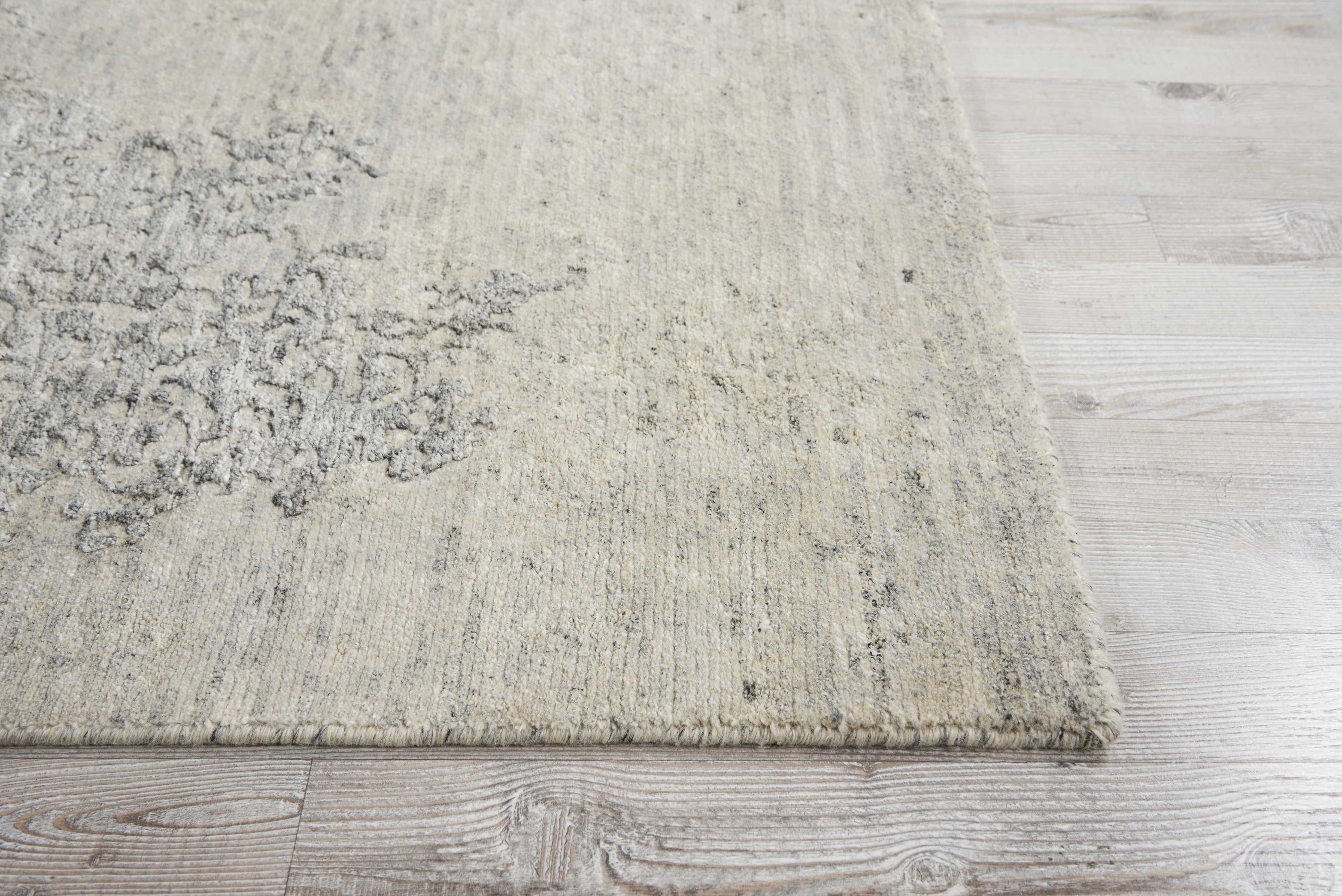 Close-up of a light-colored textured rug on a wooden floor.