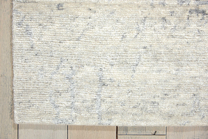Close-up view of a textured area rug on wooden floor.