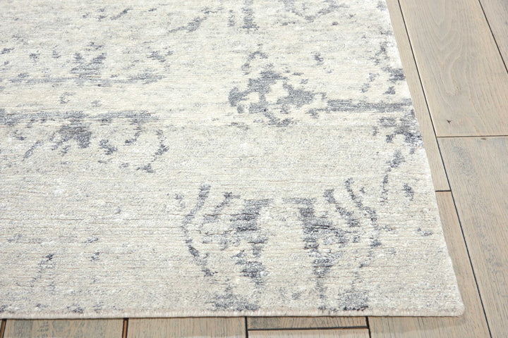 Faded gray patterned area rug adds elegance to wooden floor.