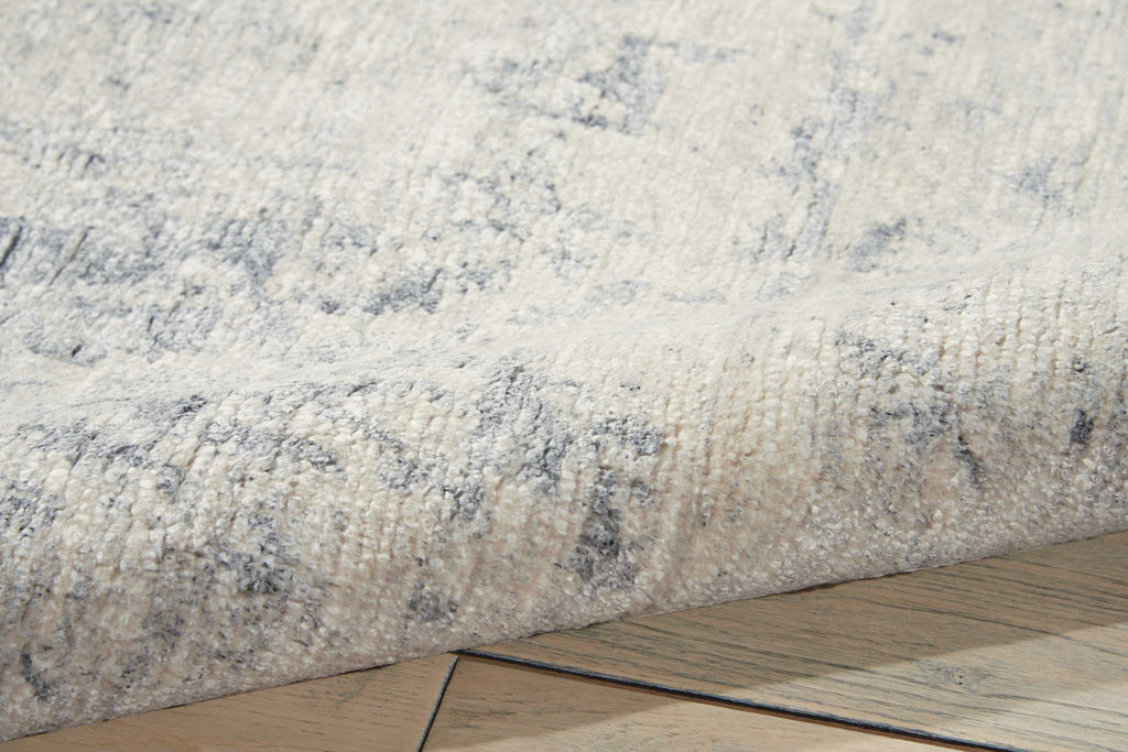 Close-up of a plush, mottled rug edge on wooden floor.