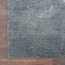 Close-up of a textured rug with speckled pattern on hardwood floor.