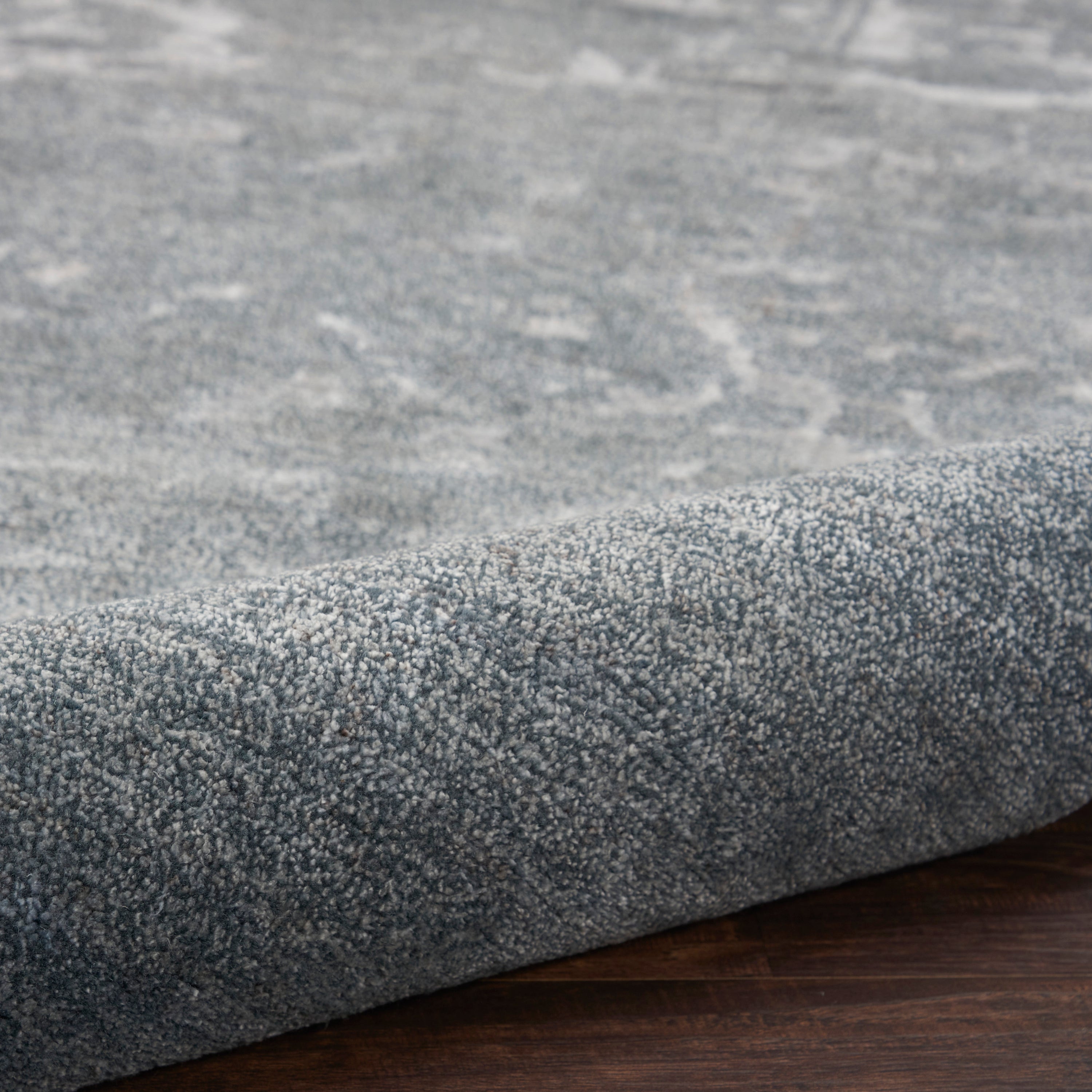 Close-up of a new, plush gray carpet on a wooden floor.