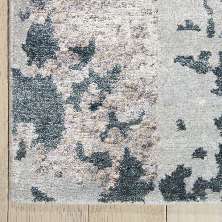 Abstract patterned rug with shades of gray on wooden floor