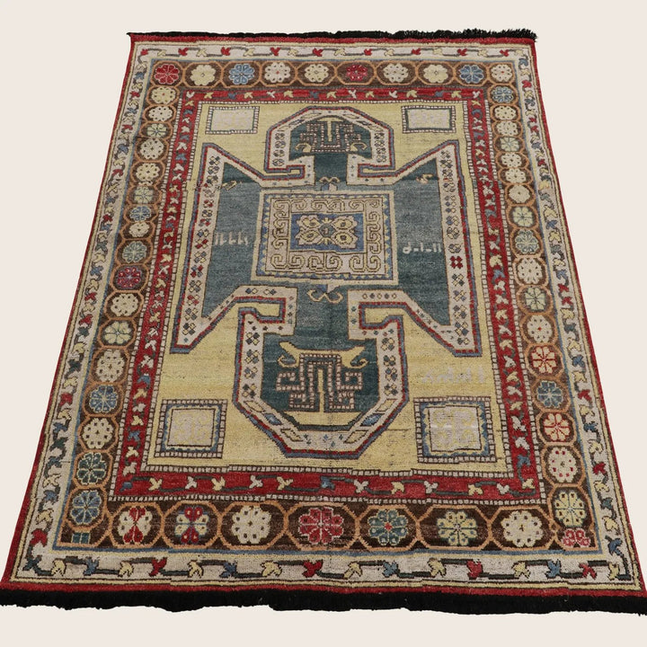 Antique, handwoven rug with intricate geometric design and earth tone palette.