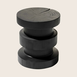Modern minimalist black tower sculpture with wood grain patterns.