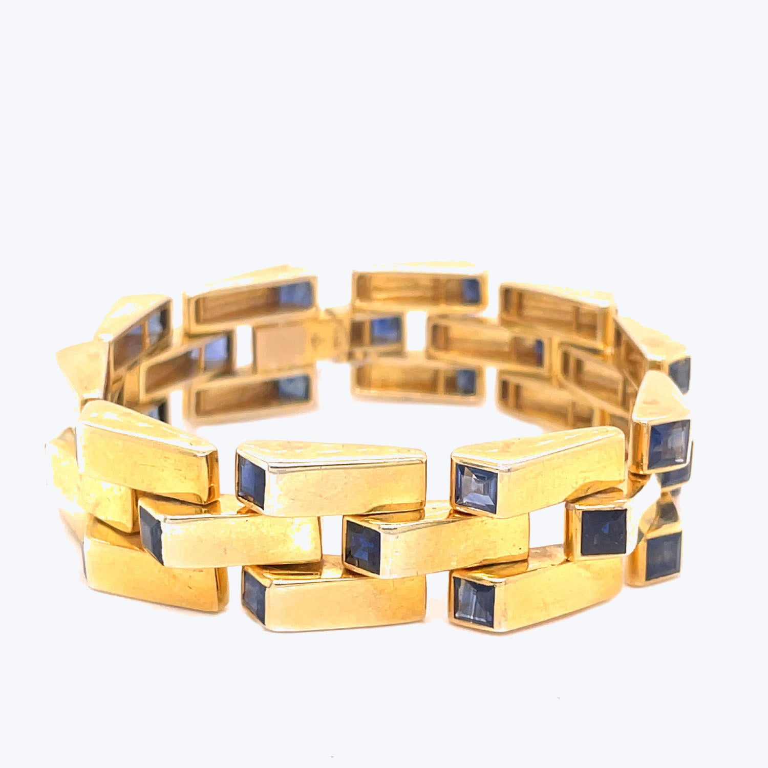 Elegant gold bracelet with geometric design and blue gemstone accents.