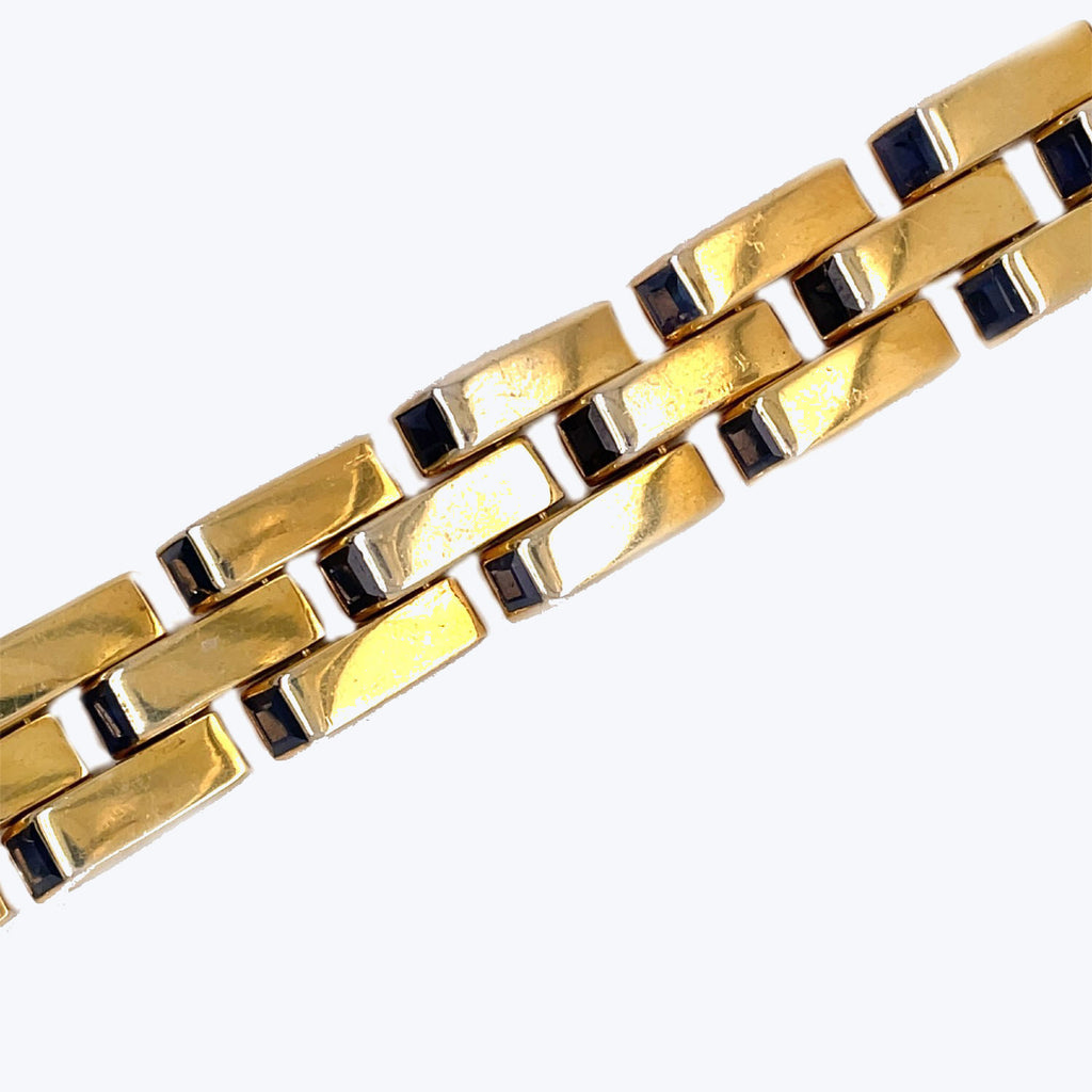 Gold-toned bracelet with rectangular links and black gemstone embellishments.