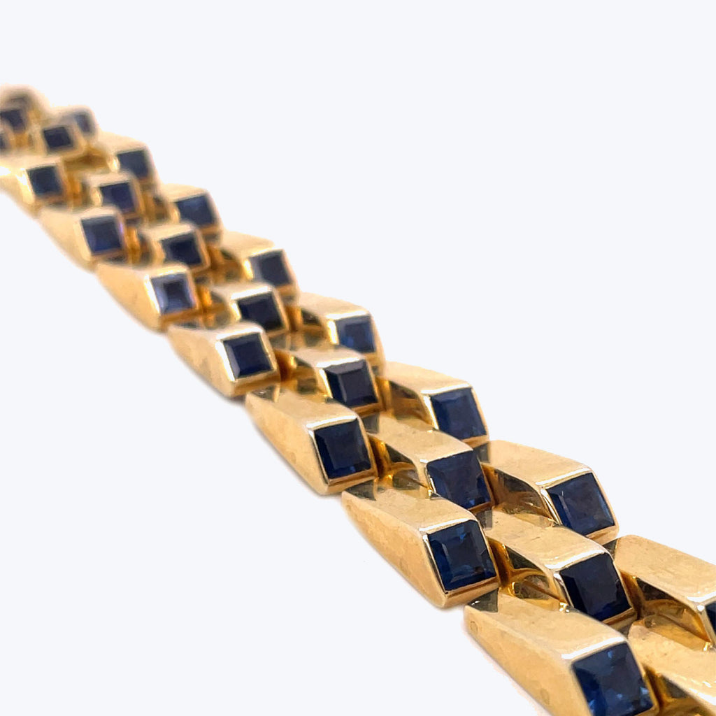 Close-up of a gold bracelet with blue sapphire gemstones.
