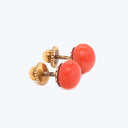 Simple and stylish orange studs with gold-toned textured settings.