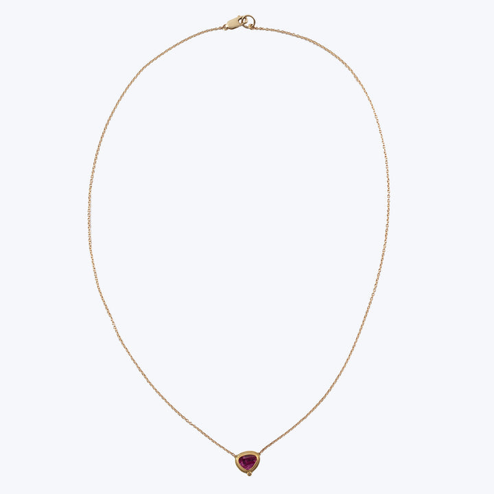 Dainty gold necklace with pear-shaped gemstone pendant on fine chain.