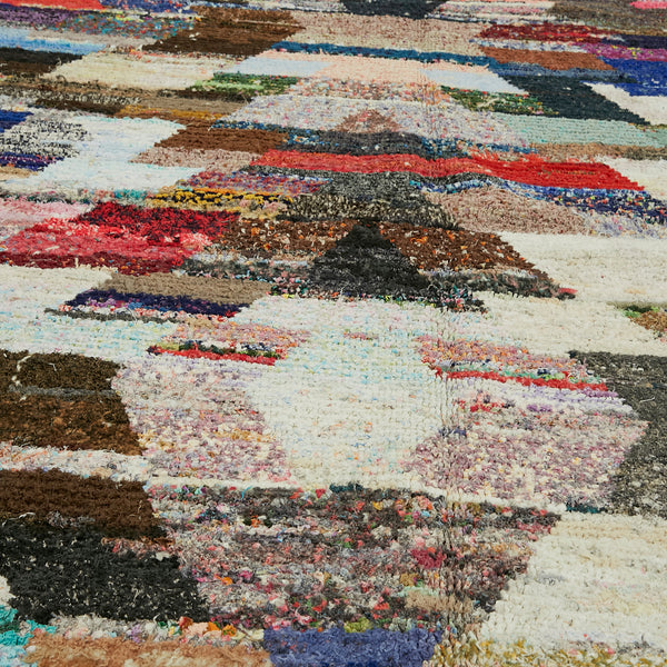 Eclectic arrangement of colorful textile fragments creates vibrant rug collage.