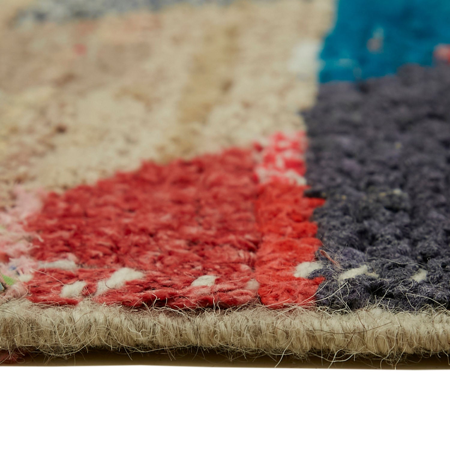 Close-up of a textured, colorful handwoven rug with frayed edges.