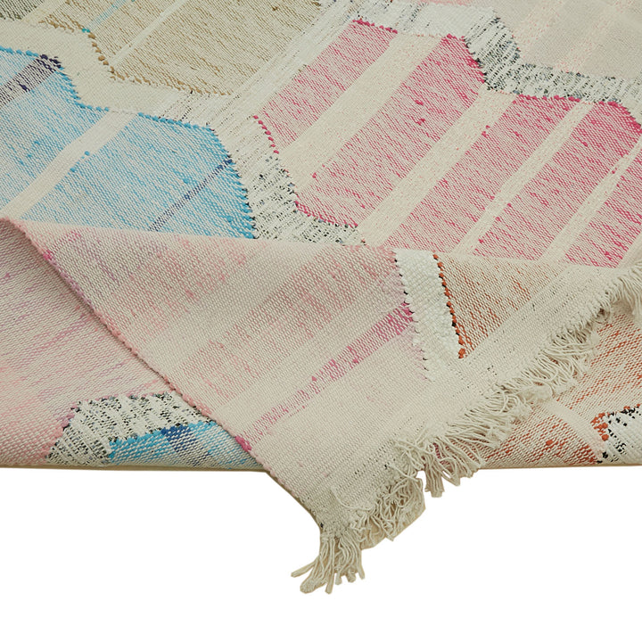 Artisanal woven rug with soft pastel colors and geometric patterns.