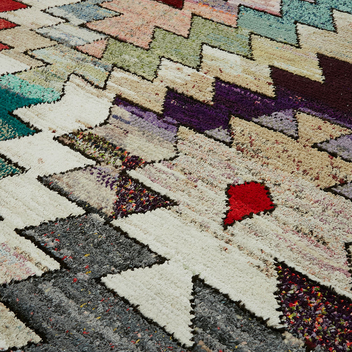 Multi-colored, textured rug with angular geometric pattern and speckled segments.