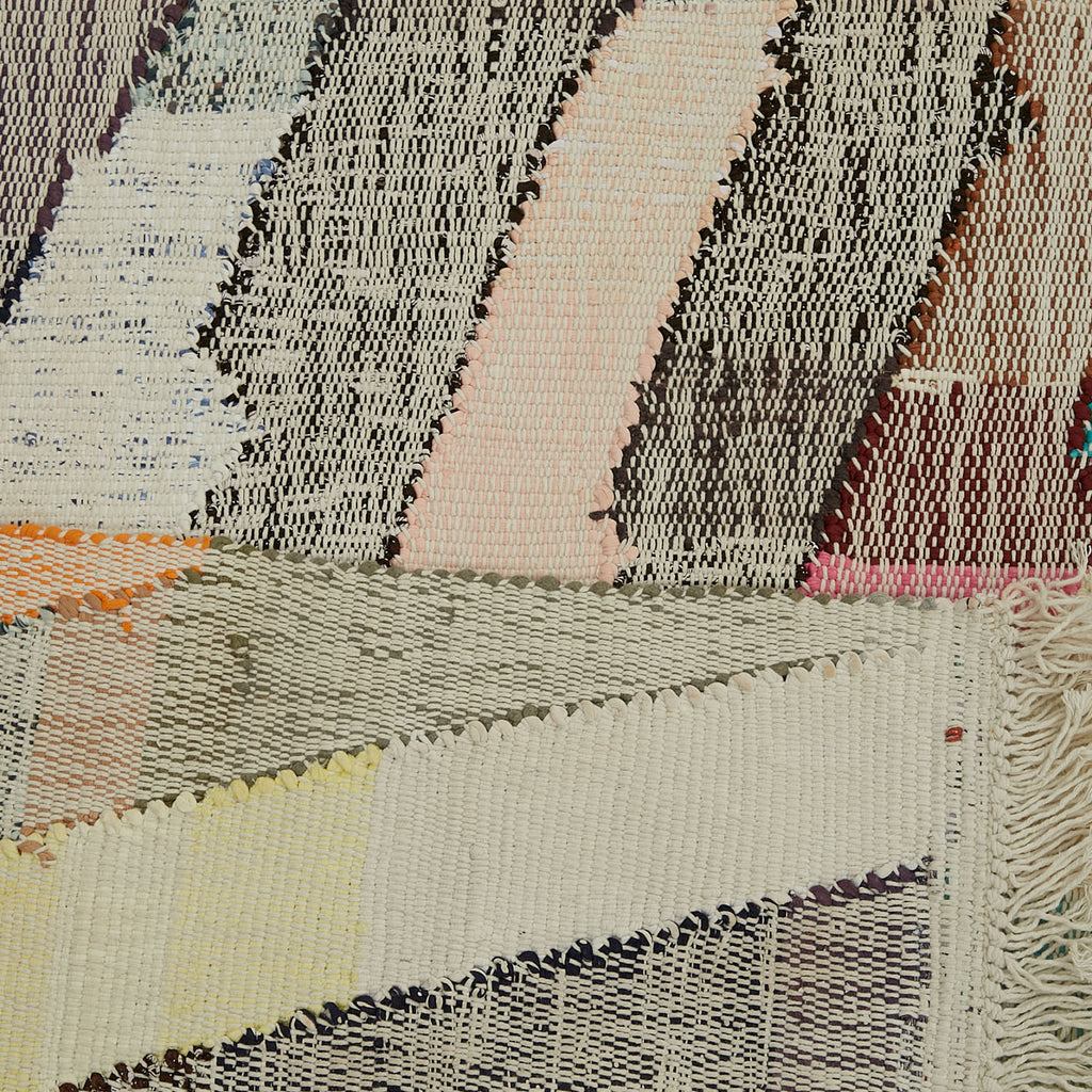 Intricate woven textile with diverse patterns, colors, and fringe details.