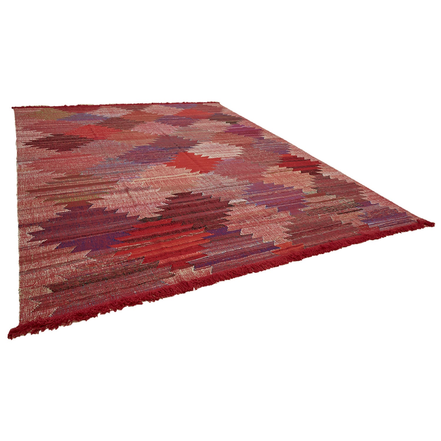 Colorful, abstract rug with irregular edges and artisanal fringe detail.