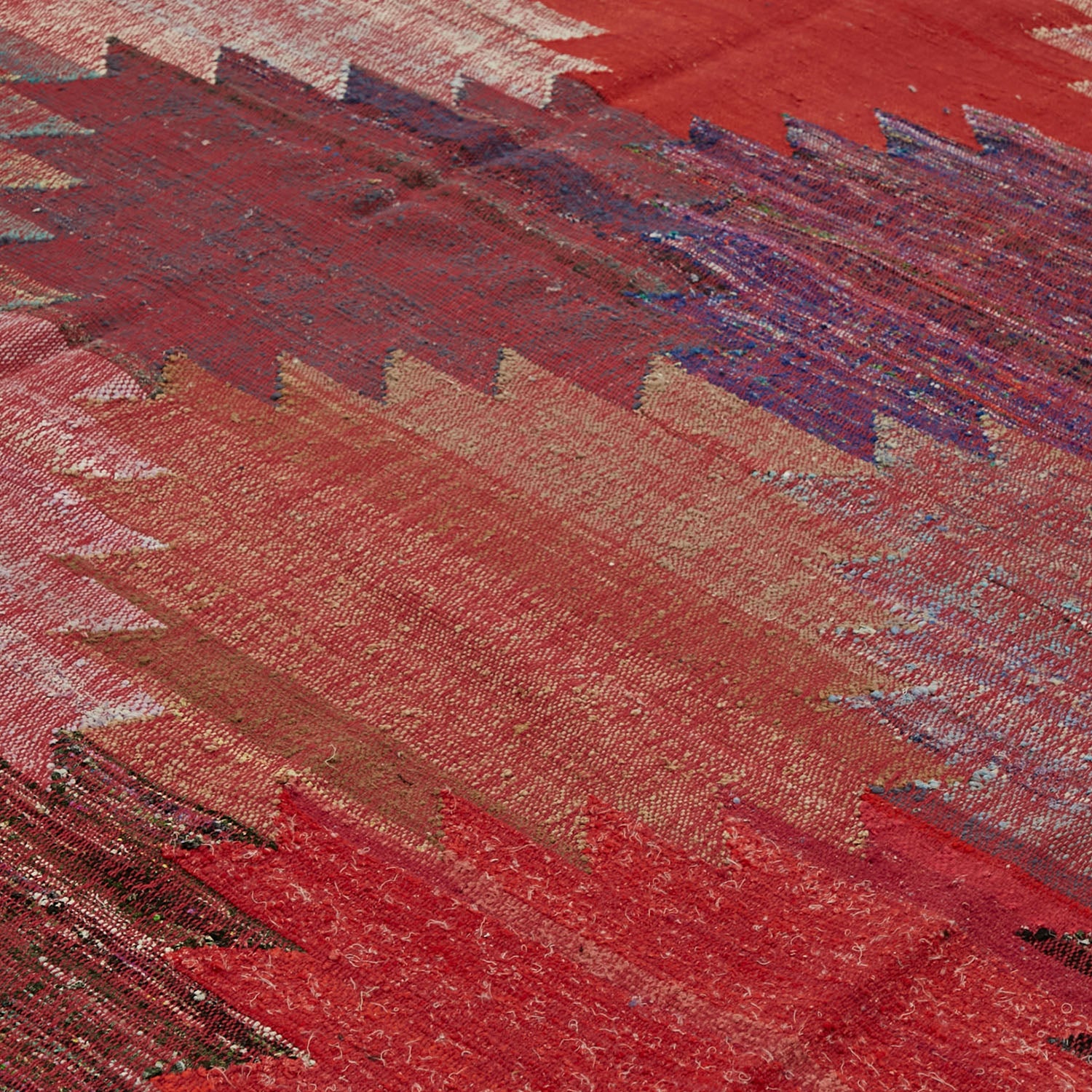 Close-up of a richly textured woven fabric in red hues.