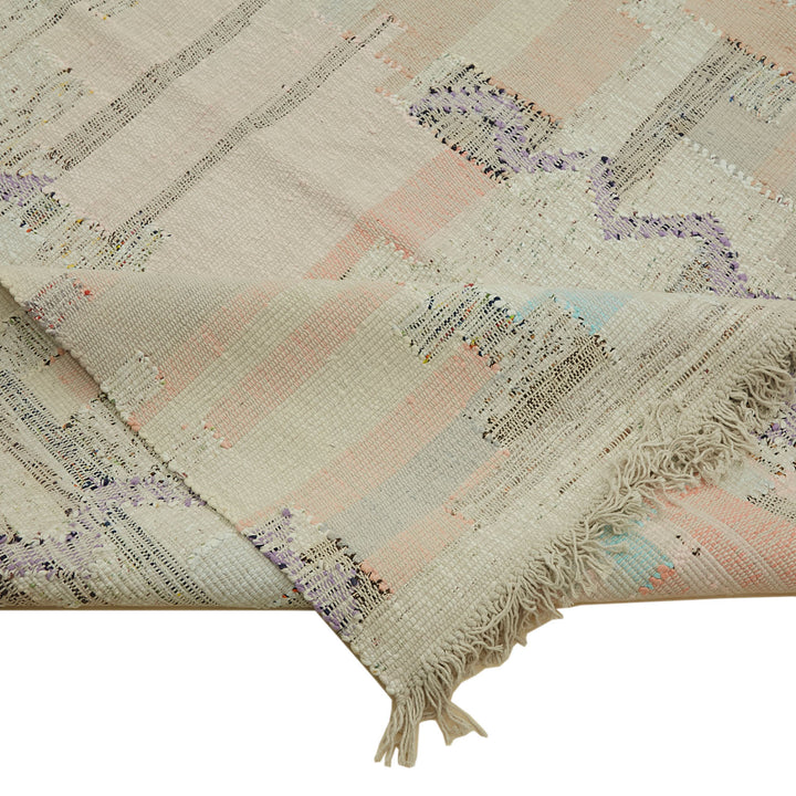 Close-up of a textured, striped blanket with fringed edges.