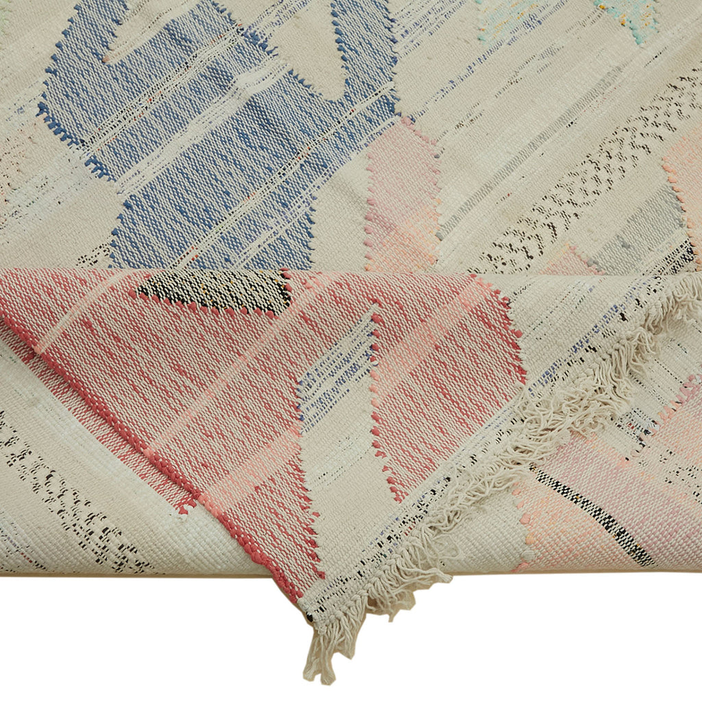 Close-up of intricately patterned textile with fringed edges and label.