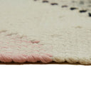 Close-up of a rug with pink scalloping and creamy texture.