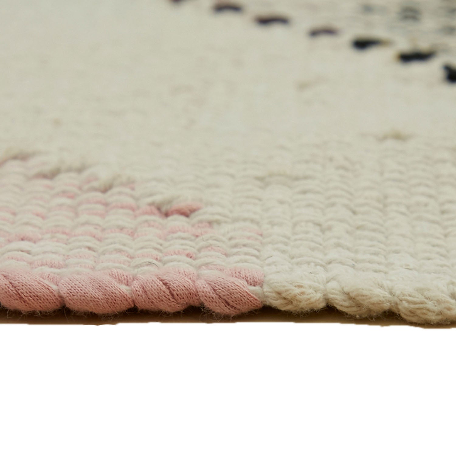 Close-up of a rug with pink scalloping and creamy texture.