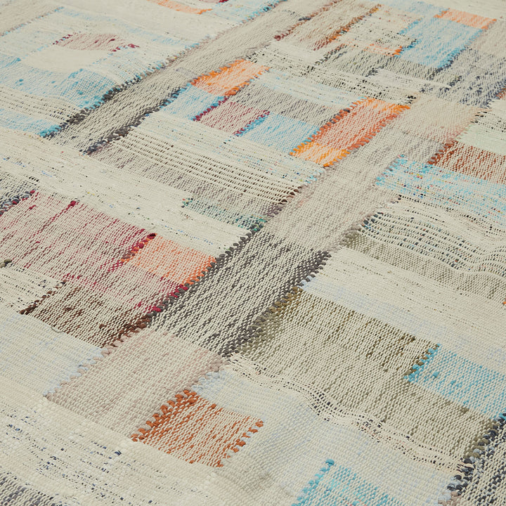 Hand-woven rug showcases a vibrant, abstract grid-like design in various colors.