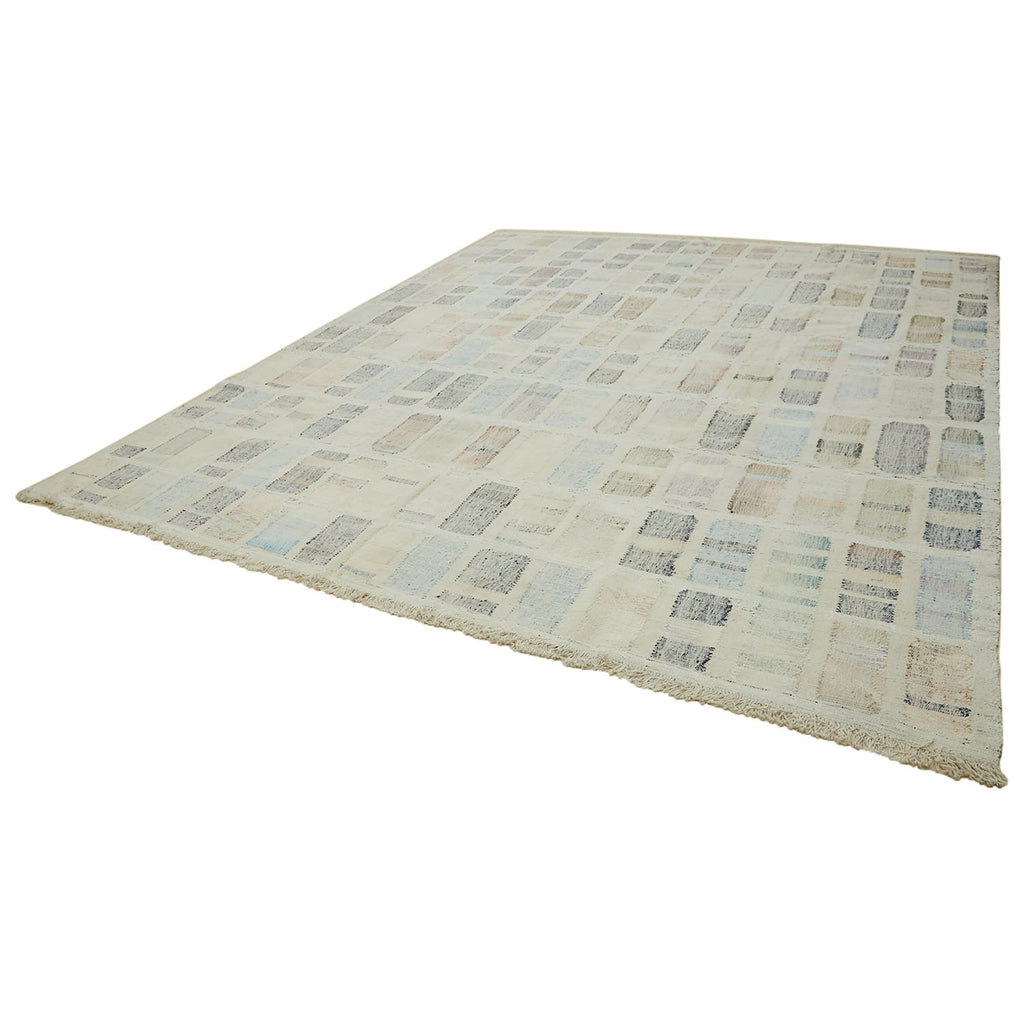 Sophisticated rectangular rug with patchwork-like design and muted tones.