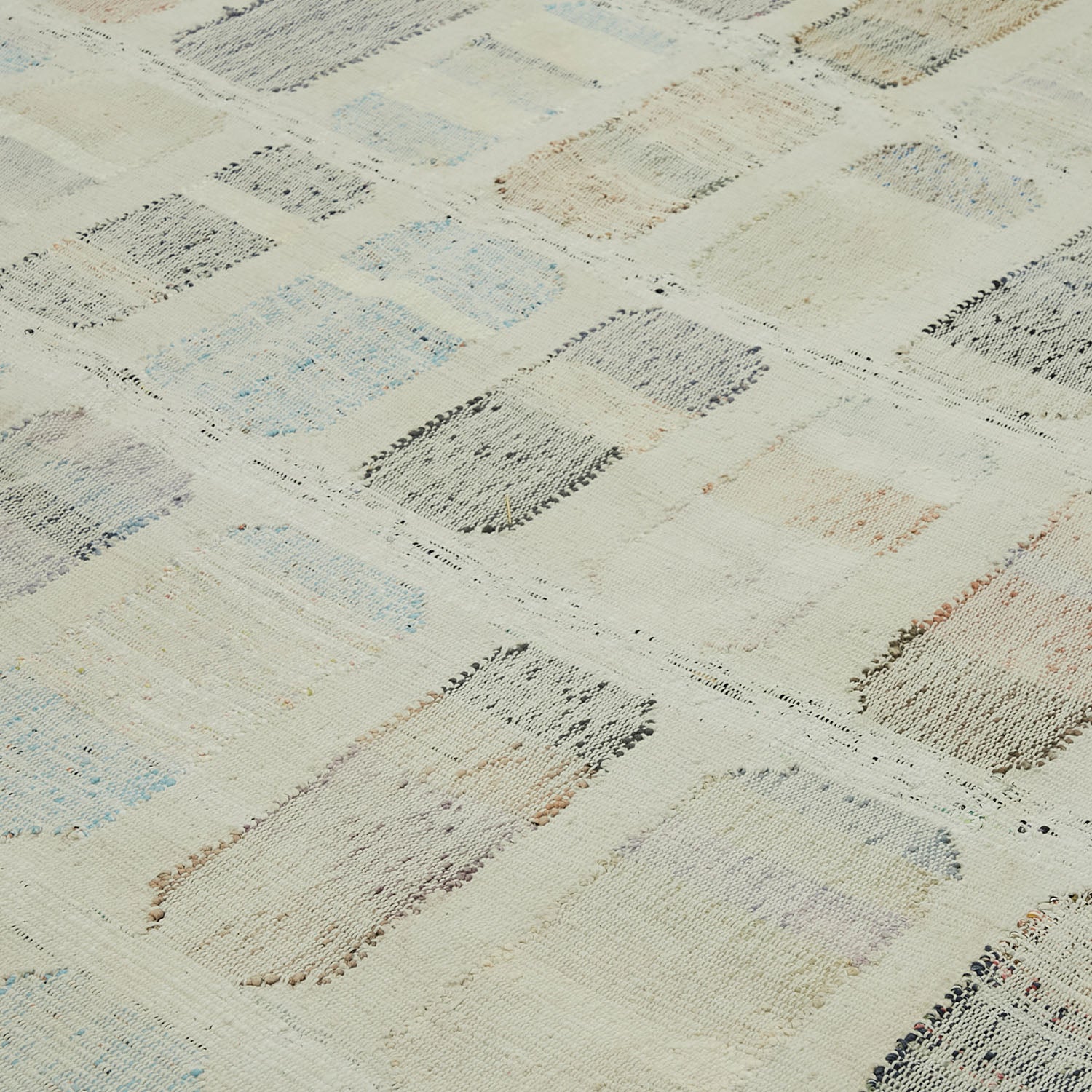 Close-up of abstract patterned fabric with pastel tones and texture.