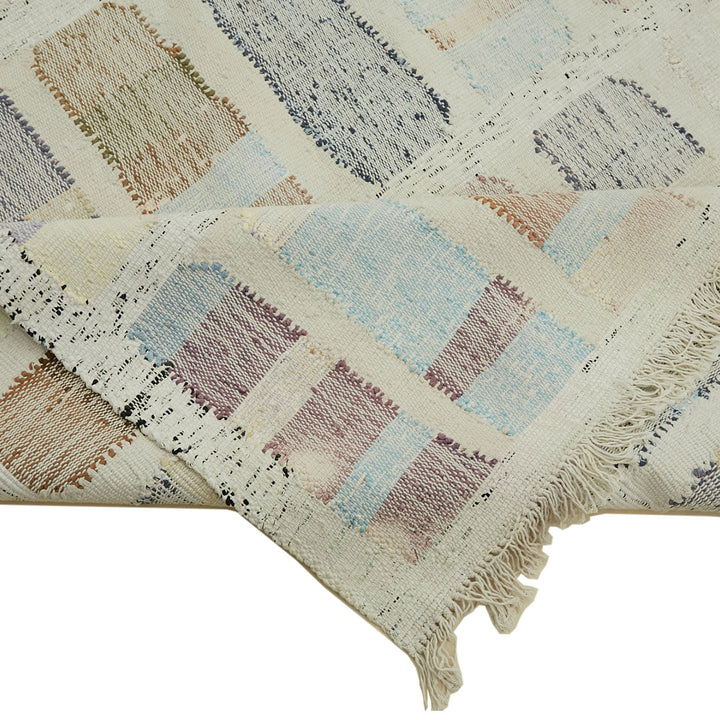 Fringe-edged textile with rectangular blocks in rustic patchwork design.