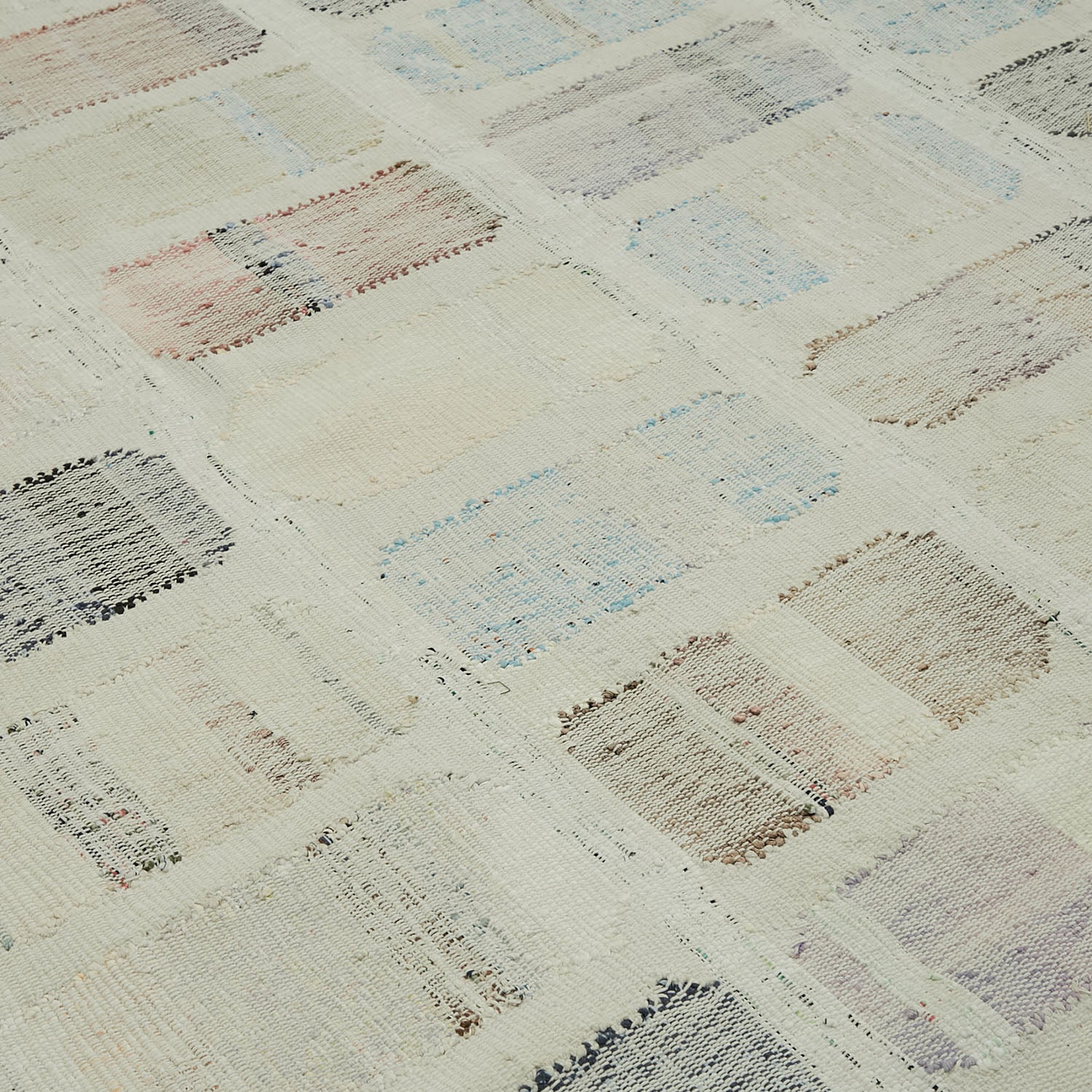 Close-up view of a patchwork rug with diverse textured squares