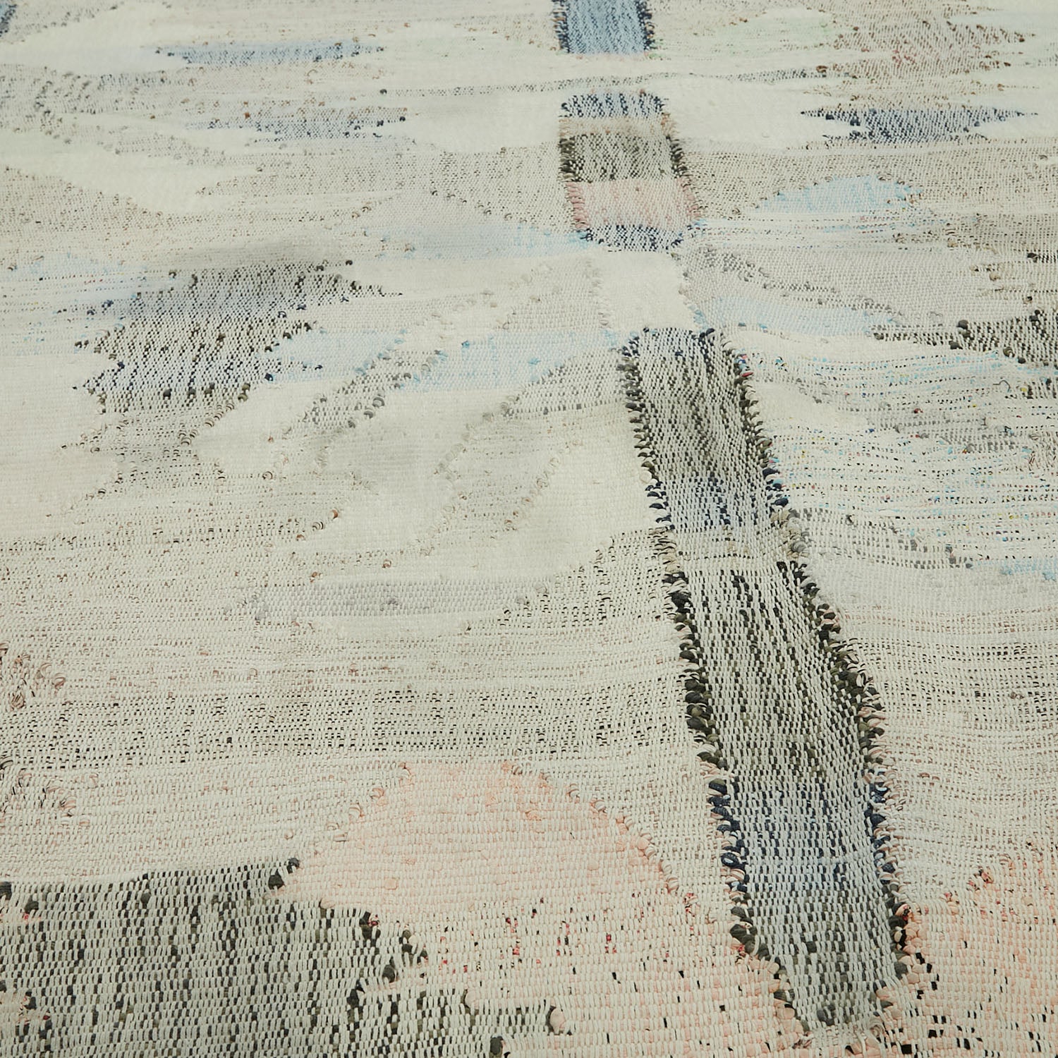 Close-up of a textured woven fabric with frayed edges and varied colors.