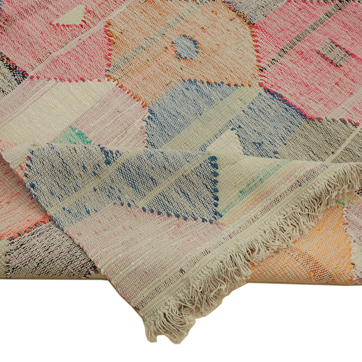 Handcrafted woven rug with geometric pattern and muted colors.