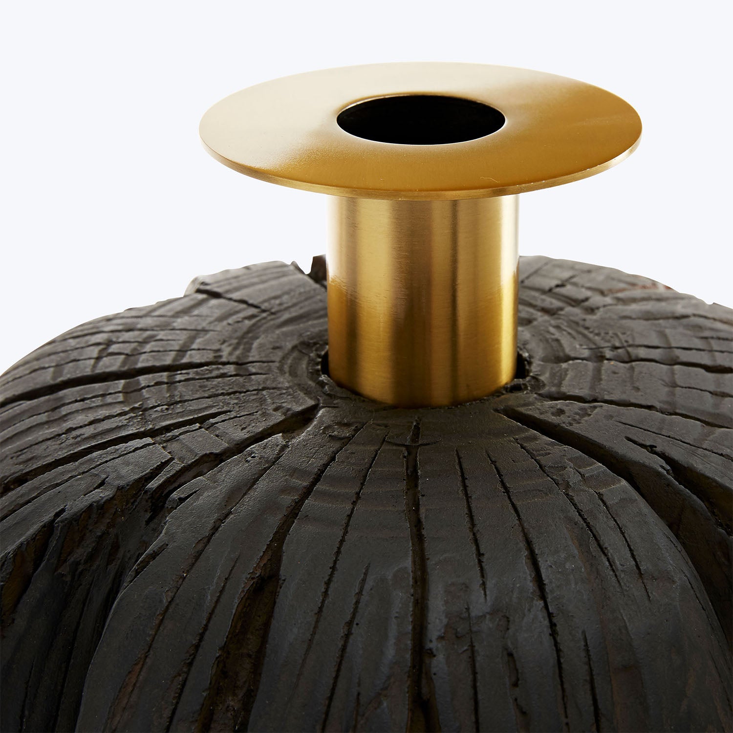 Black textured surface with a gold cylindrical centerpiece on it.