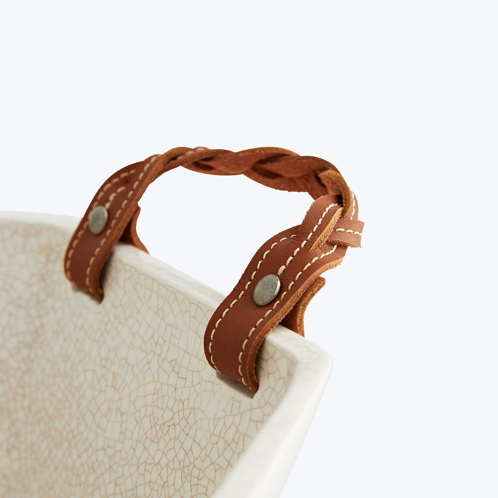 Braided leather handle on off-white textured bag with double stitching