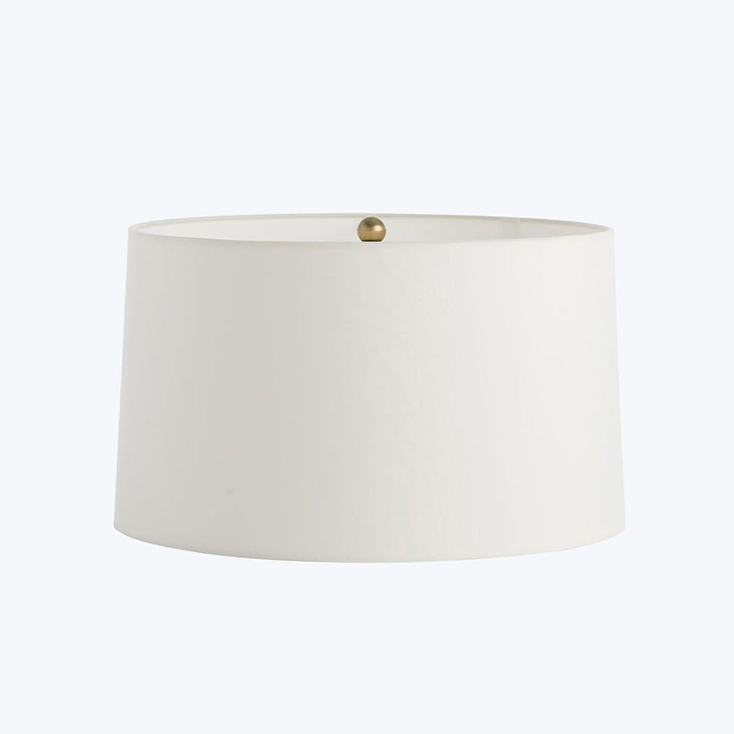 Simple white lampshade with metallic finial against a plain background.
