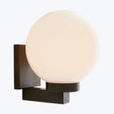 Modern wall-mounted lighting fixture with large spherical lampshade emits soft, diffuse light.