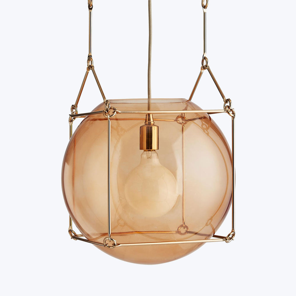 Modern amber pendant light with brass fixture and adjustable height.
