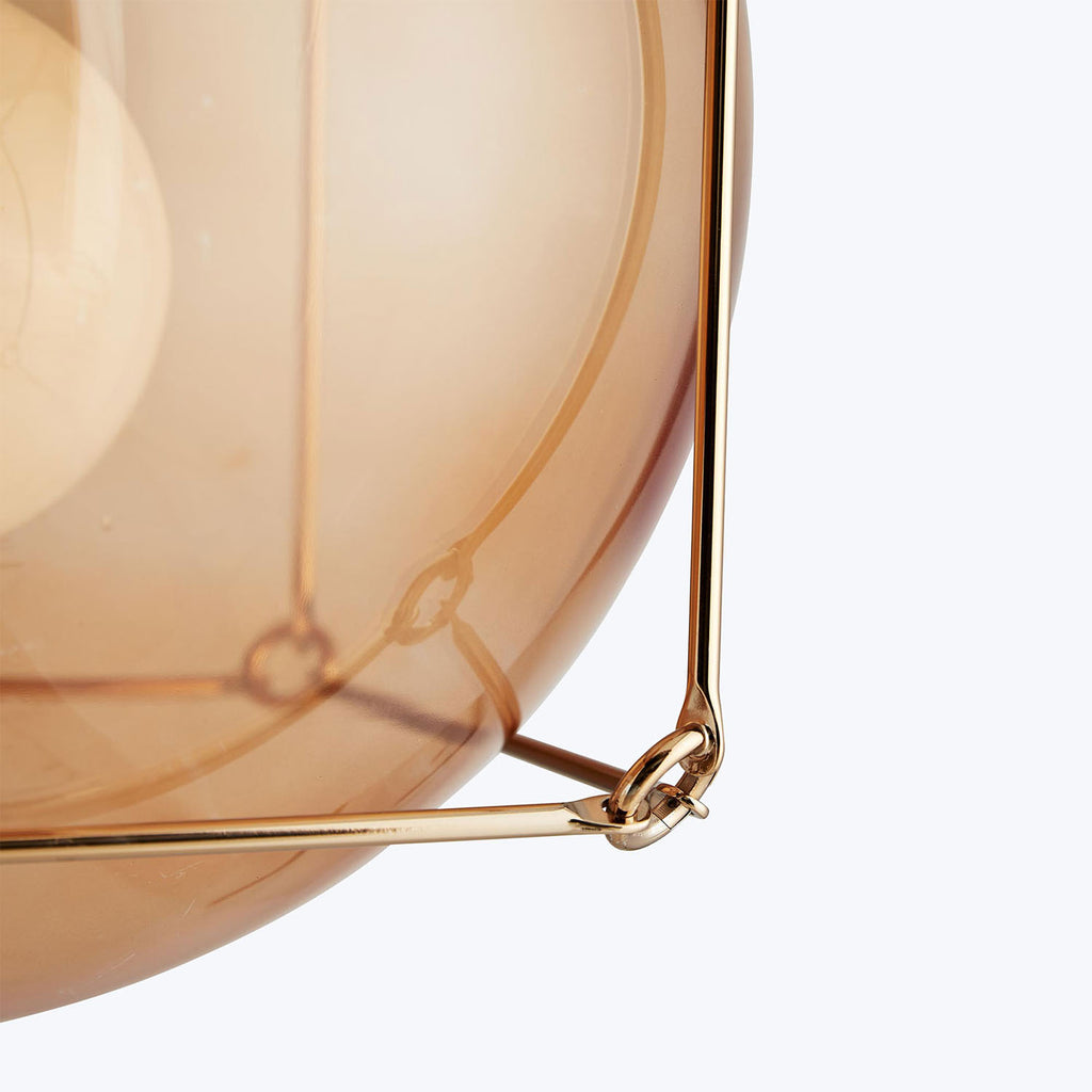 Close-up of warm beige glass sphere with elegant brass frame.