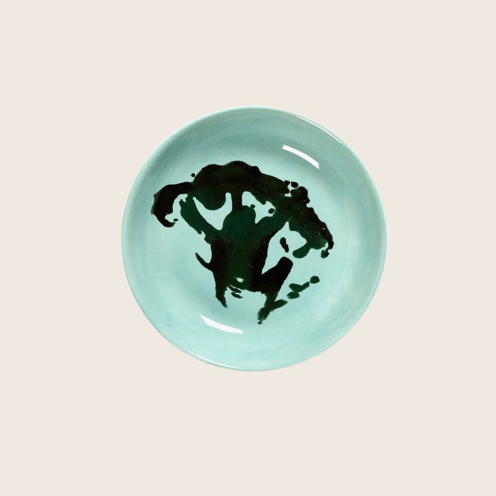 Ceramic bowl with aqua glaze and abstract black ink blot.