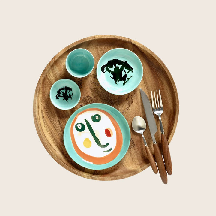 Artistic wooden tray with globe-inspired dishes and cutlery arrangement.