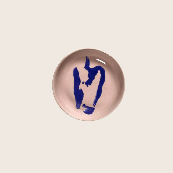 Abstract ceramic bowl with blue design on pale pink interior.