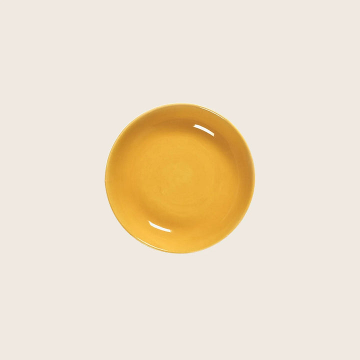 Vibrant yellow bowl against white background, empty and glossy finish.
