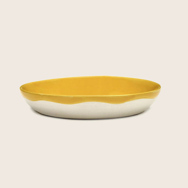 Modern oval ceramic platter with vibrant yellow interior on white background.