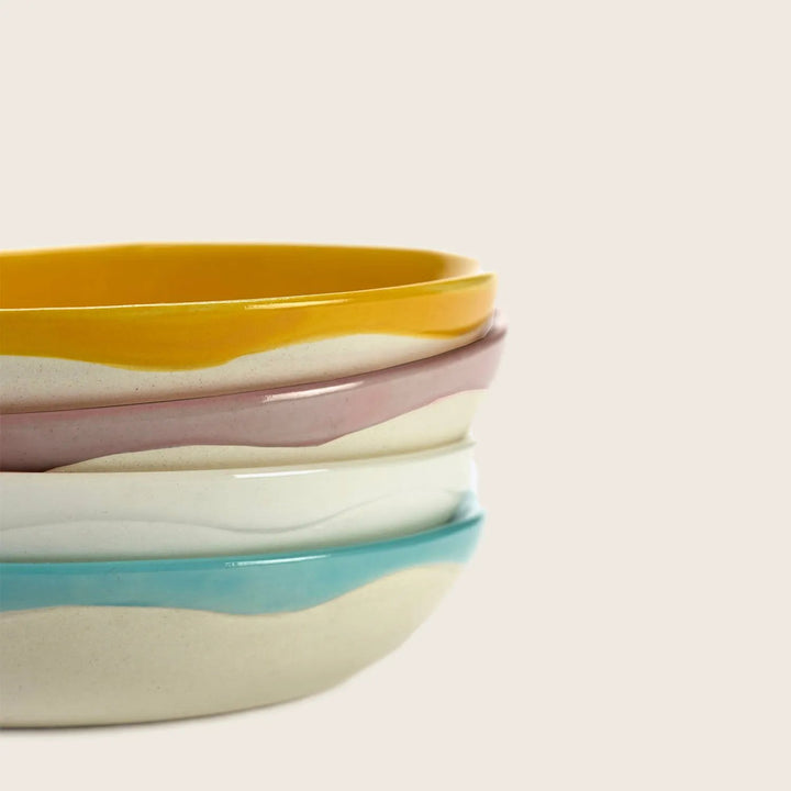 Colorful nested bowls on white background: yellow, white, pink, blue.