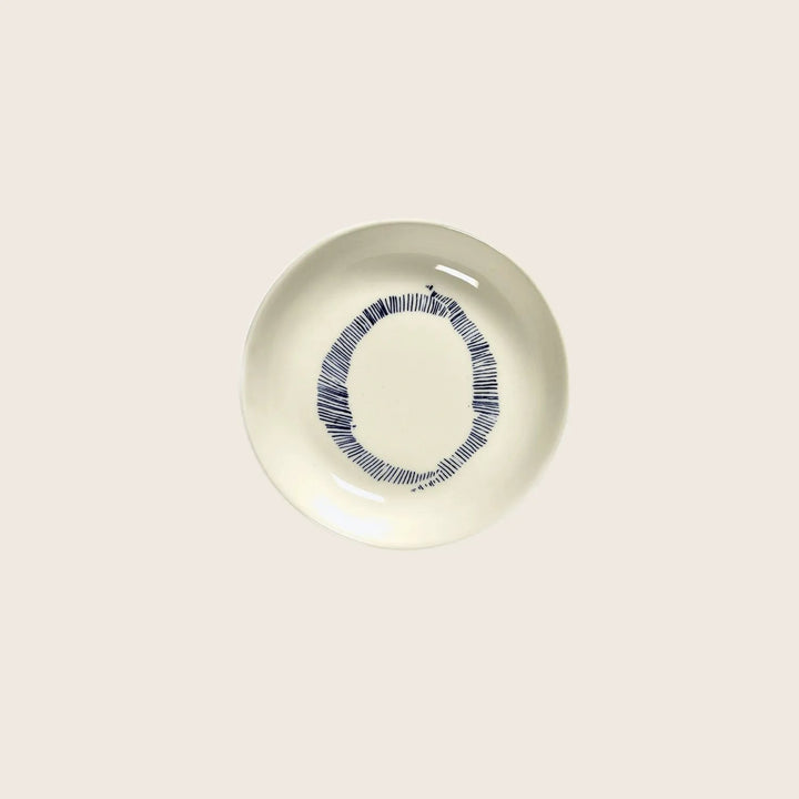 Minimalist cream ceramic plate with blue circular geometric design.